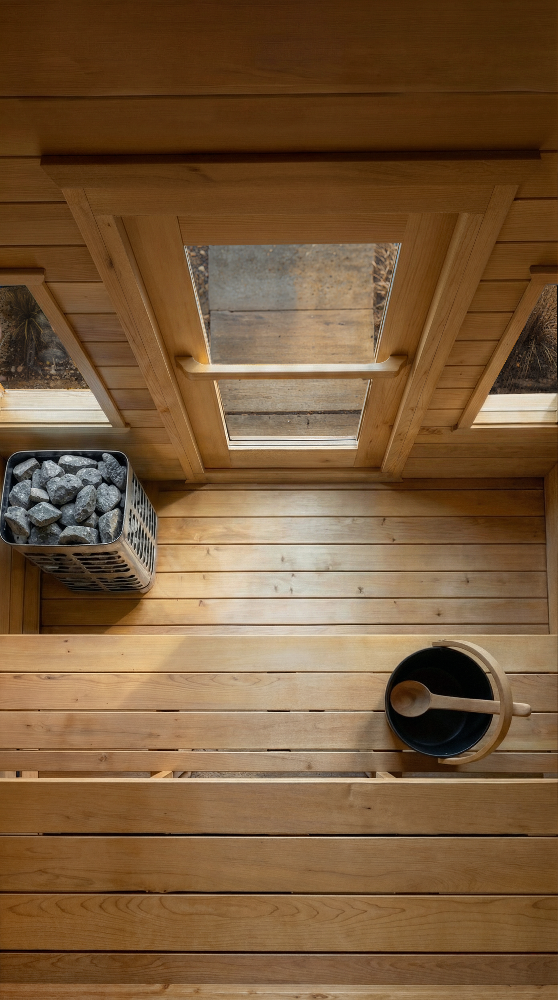 Wooden sauna interior with a windows in the door and bucket of water.