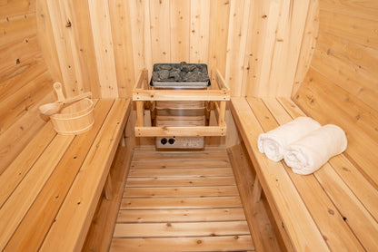 Wooden sauna interior with benches, towels, and a stone tray.