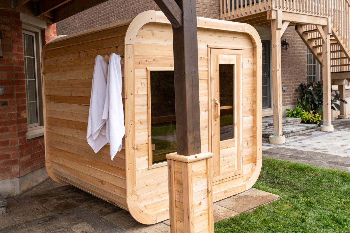 Wooden outdoor sauna with a towel hanging on a brick building
