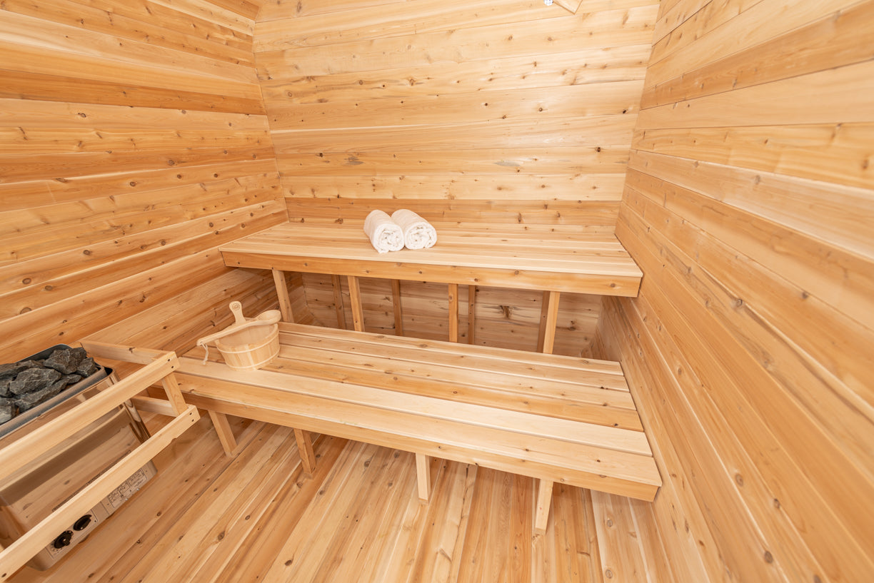 Wooden sauna interior with a bench and towels on an upper bench.