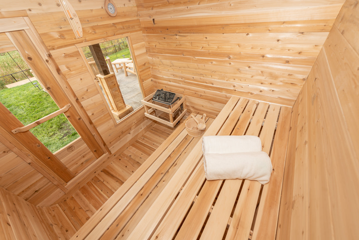 Wooden sauna with a bench and cushion, featuring a mirror and window.