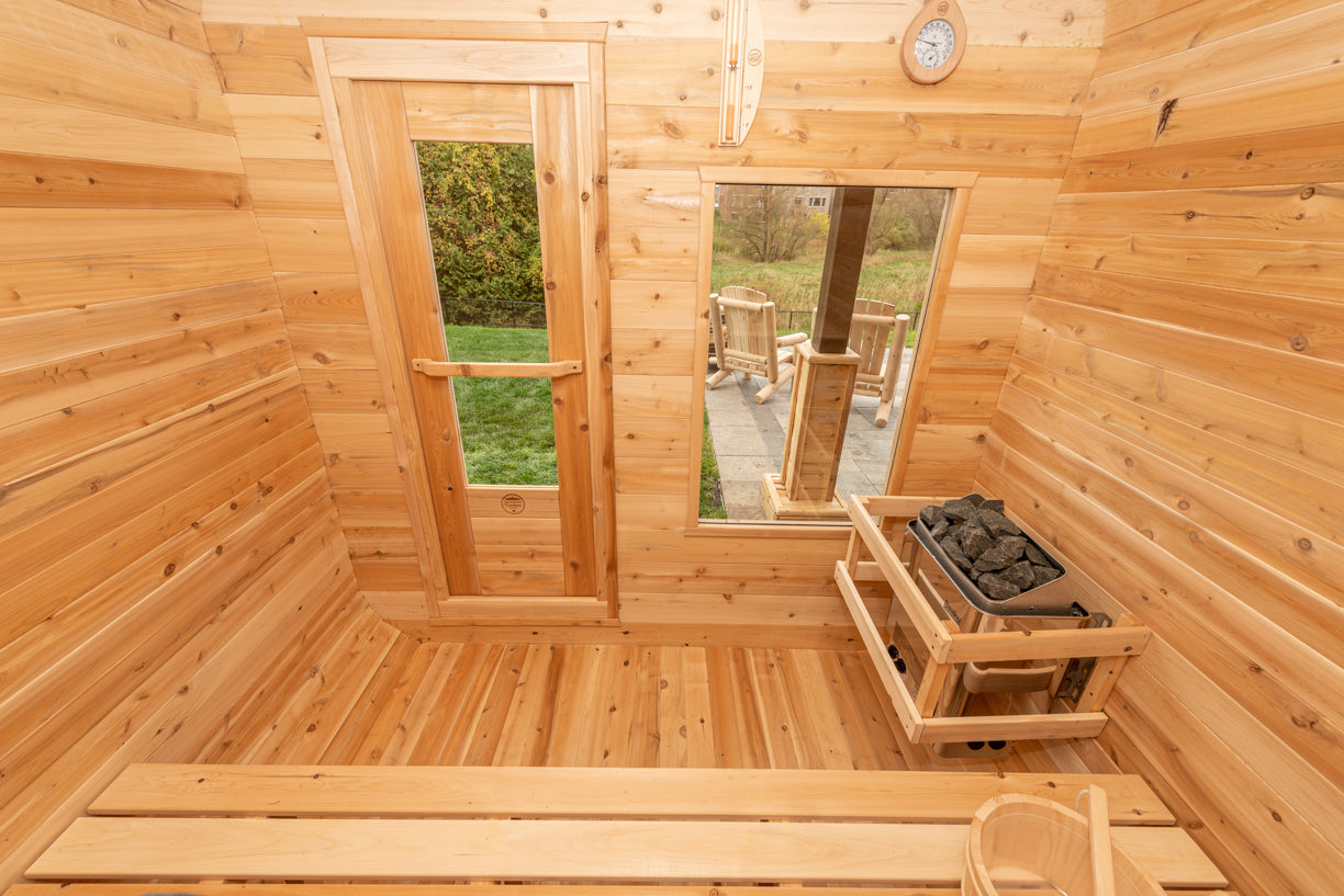 Wooden sauna interior with benches, windows, and a stove.