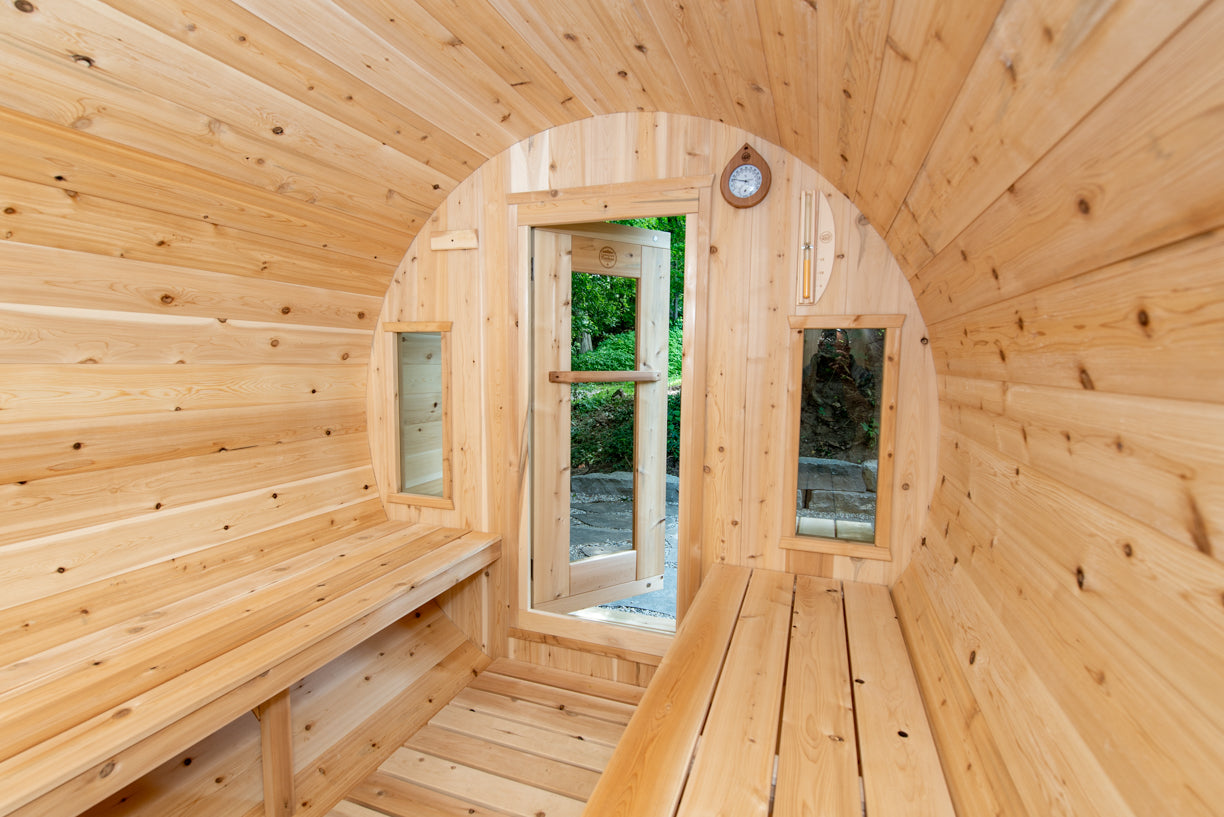 Wooden sauna with curved walls and a glass door.