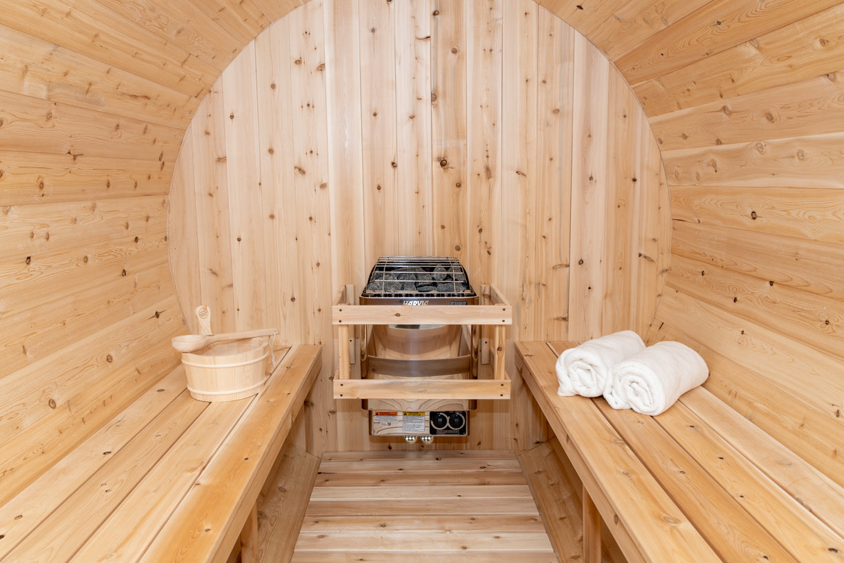 Wooden sauna with benches, towels, and a stove.