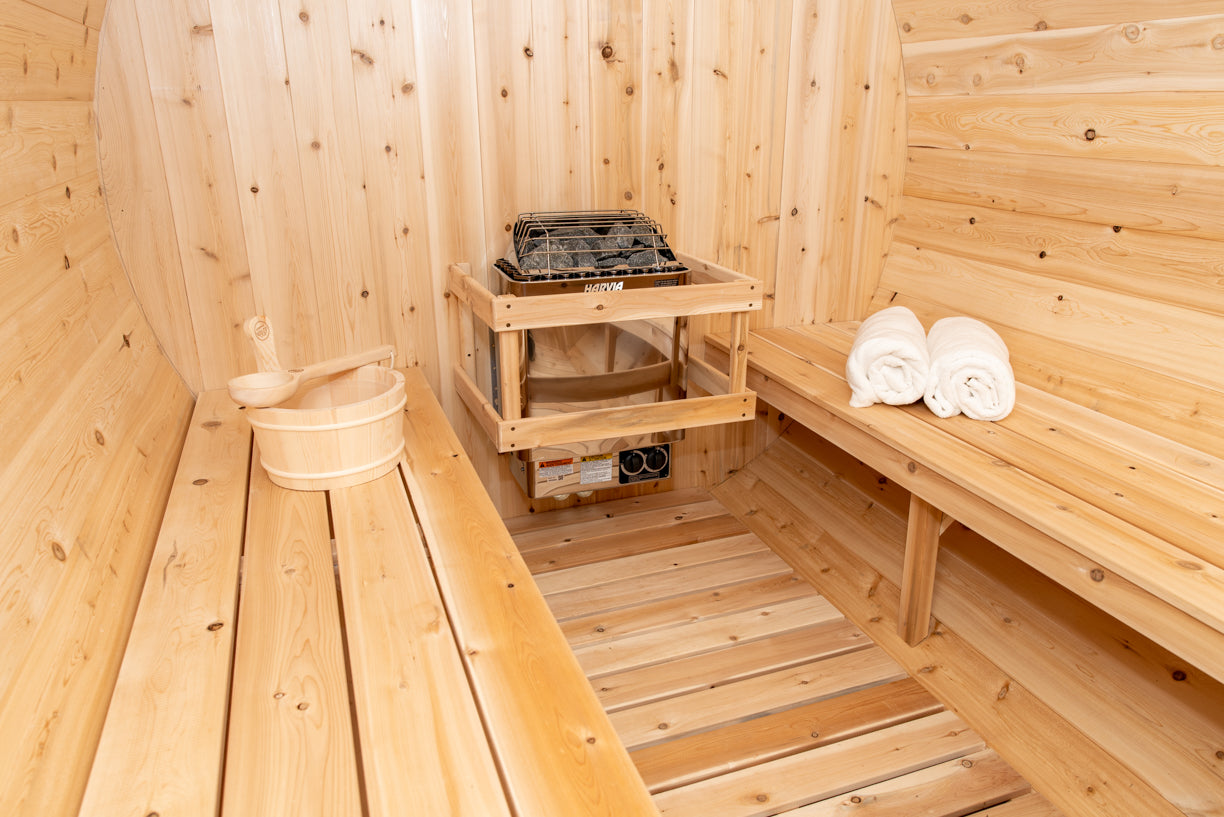 Wooden sauna interior with a shelf, towels, and a bucket.