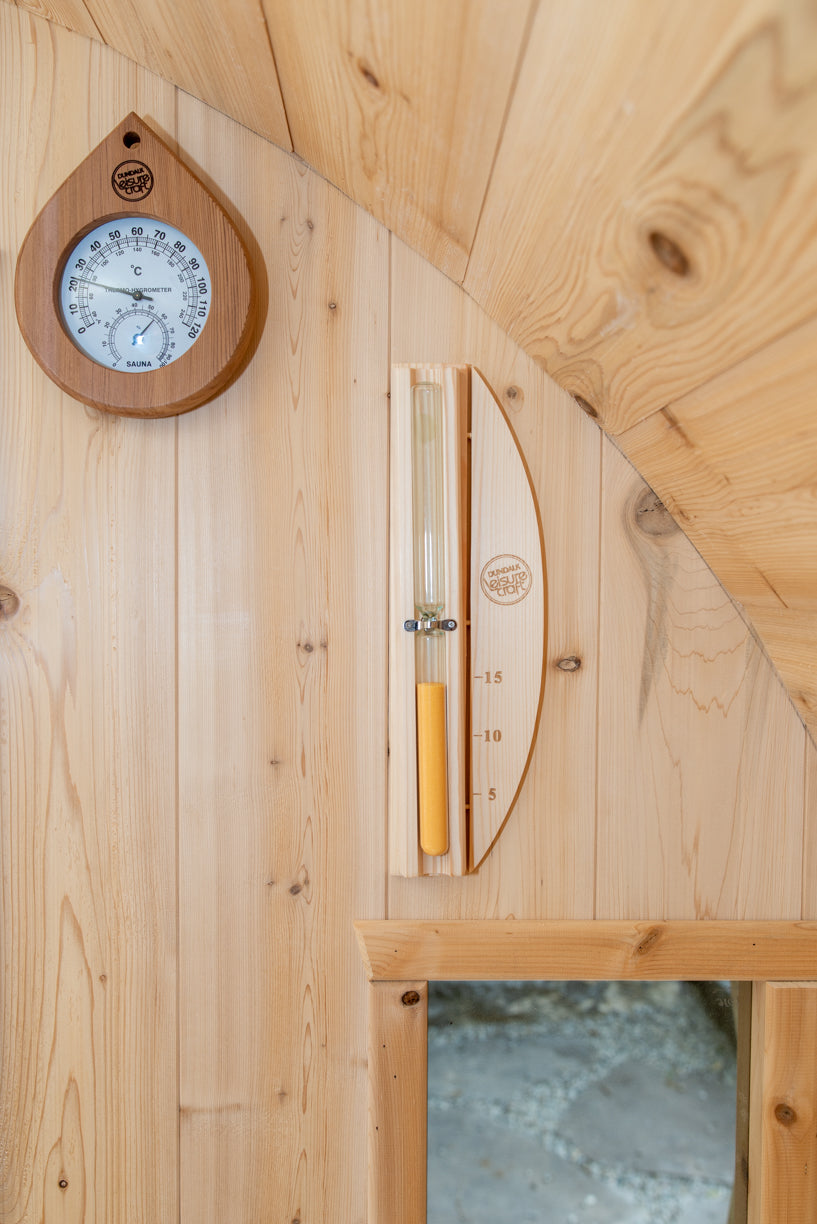 Wooden wall with a round thermometer and an hourglass  on a wooden wall.