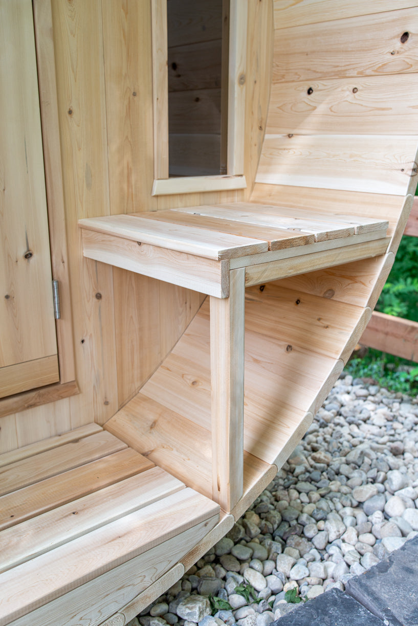 Wooden bench of barrel sauna with gravel and greenery