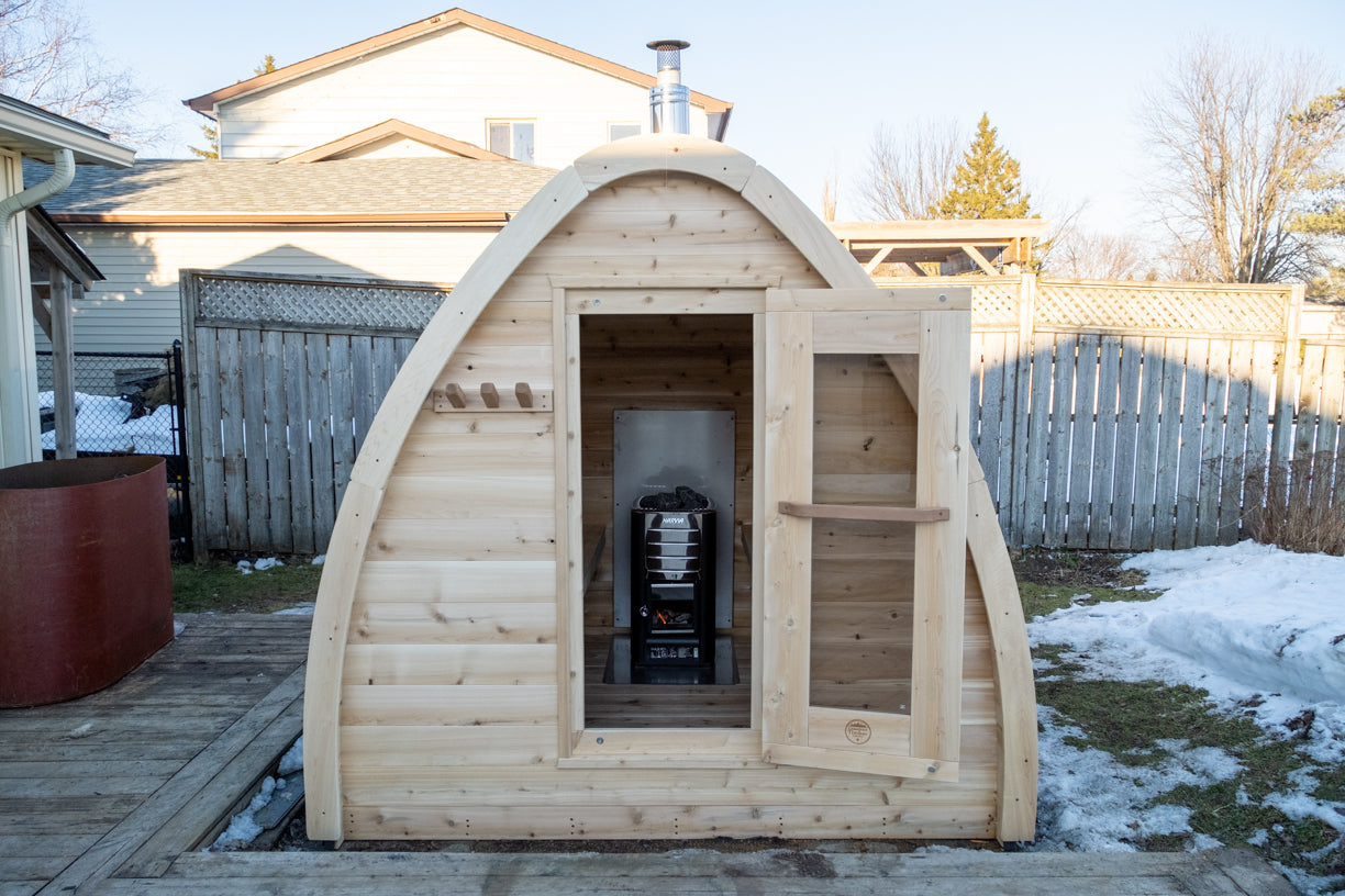 CT MiniPOD Woodburning Sauna by Leisurecraft with door open, set against a residential backyard with snow on the ground.