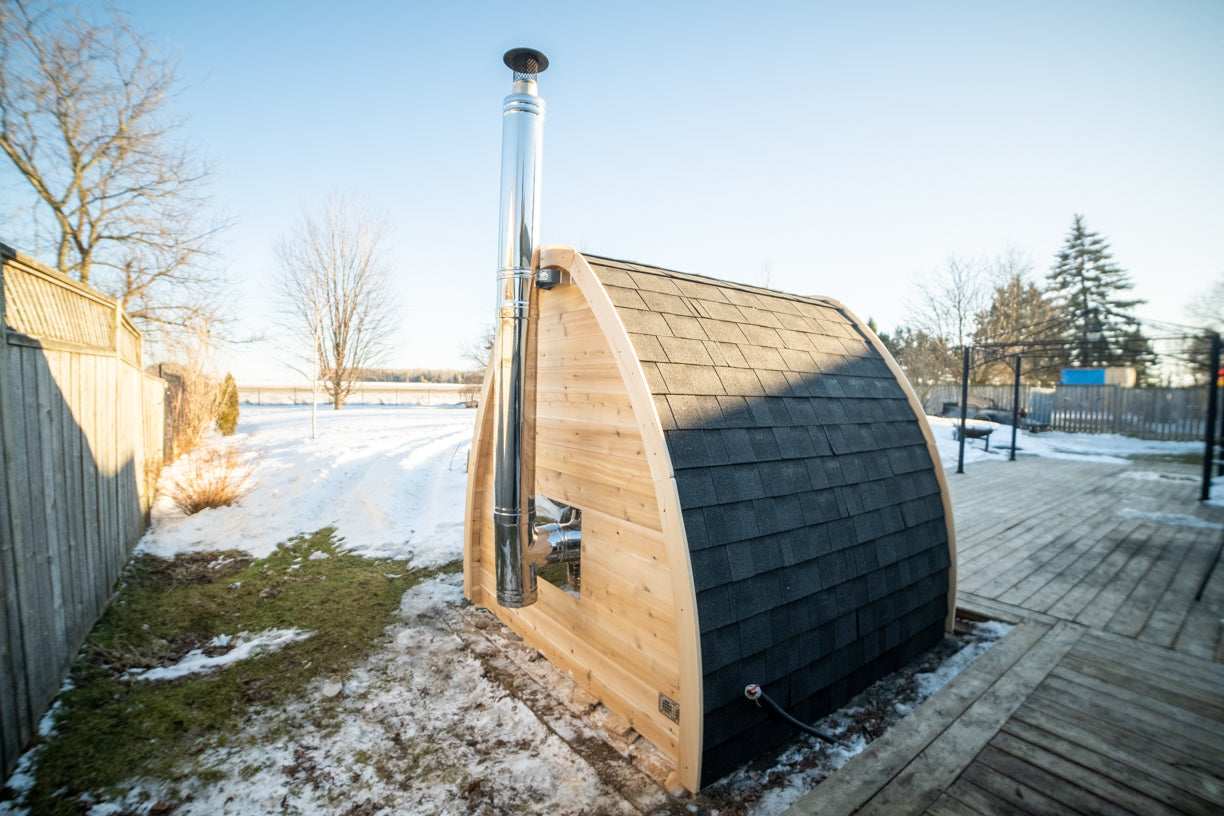 CT MiniPOD Woodburning Sauna by Leisurecraft showing the back of the sauna with a metal stovepipe on a snowy day