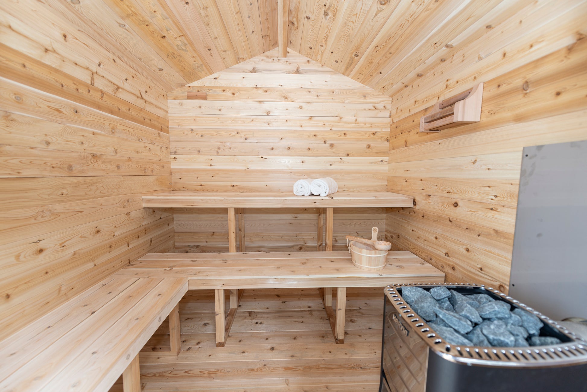 Wooden sauna interior with benches, towels, and a stove.