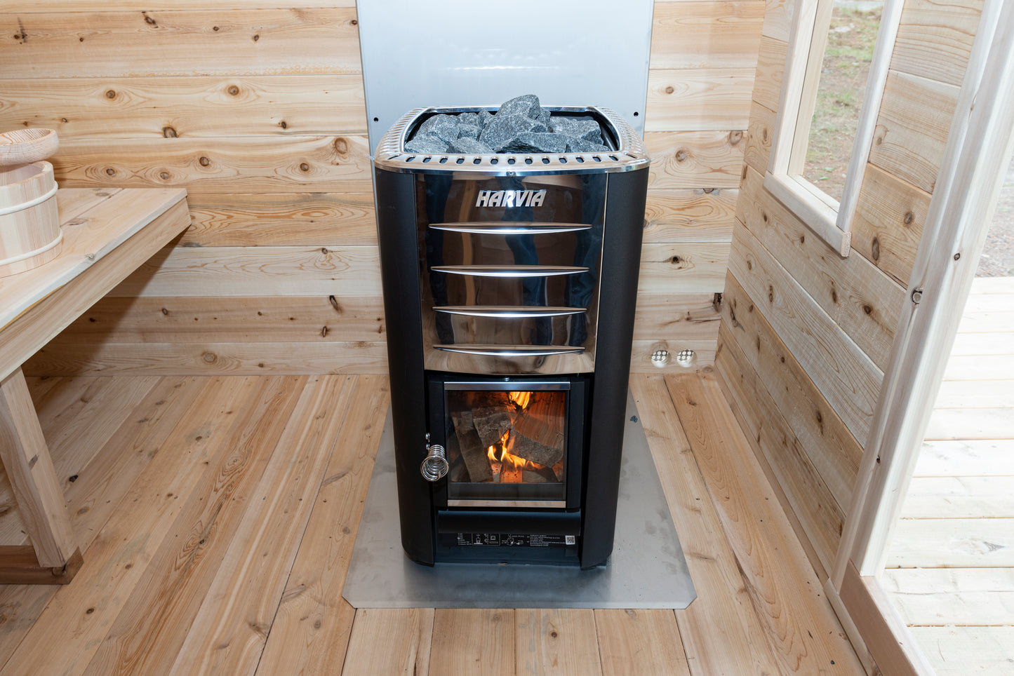 Wood-burning stove in a wooden sauna with visible brand 'Haviva'.