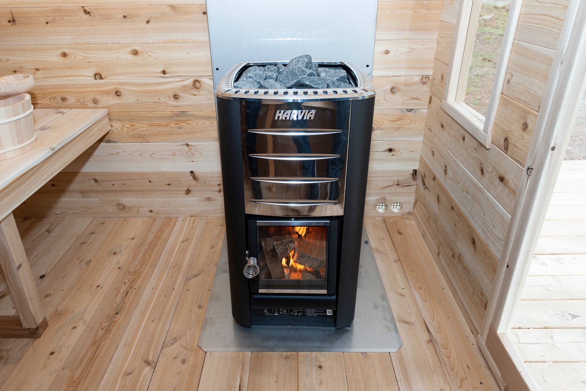 Wood-burning stove in a wooden sauna with visible brand 'Haviva'.