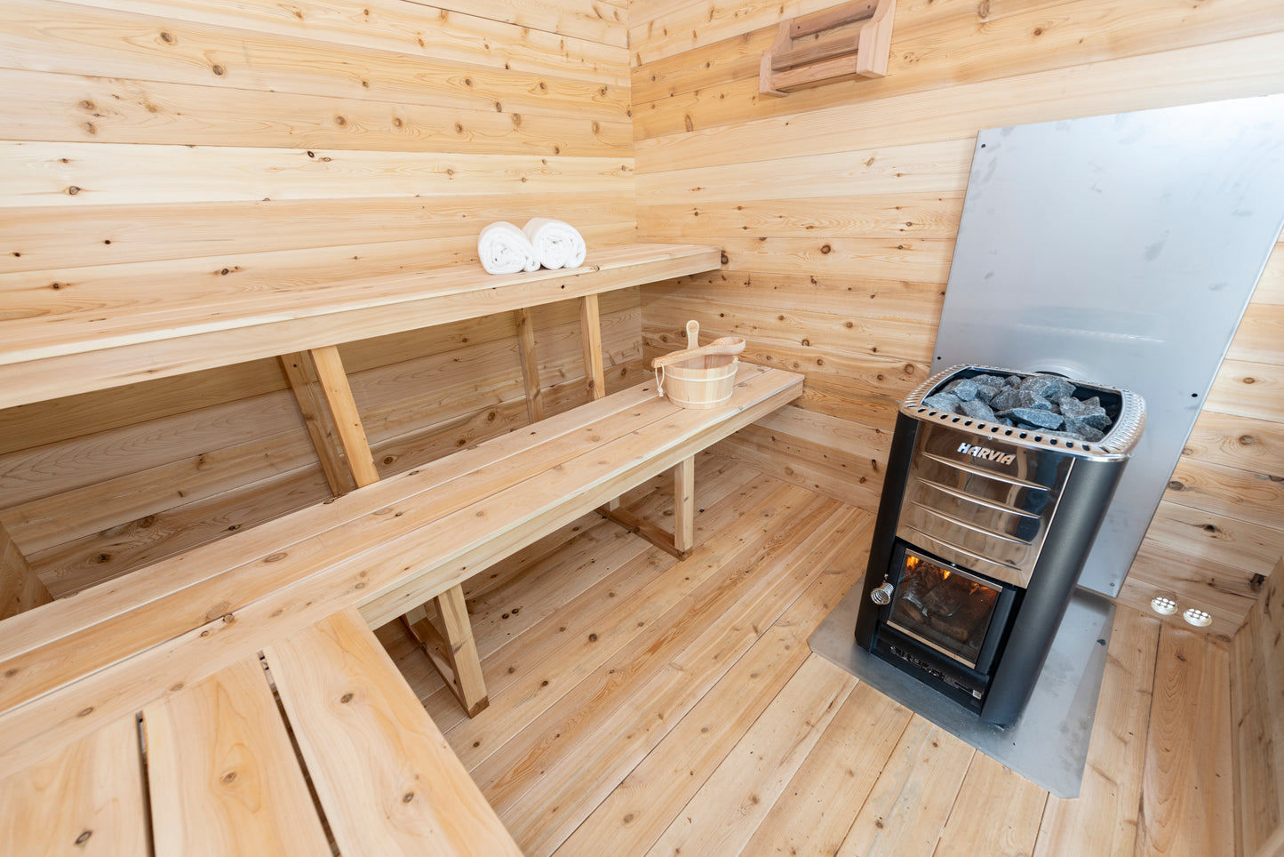 Wooden sauna interior with benches and a metal stove.