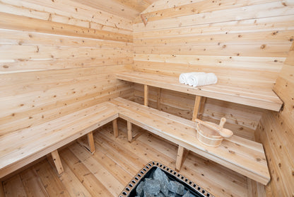 Wooden sauna interior with benches and a bowl.