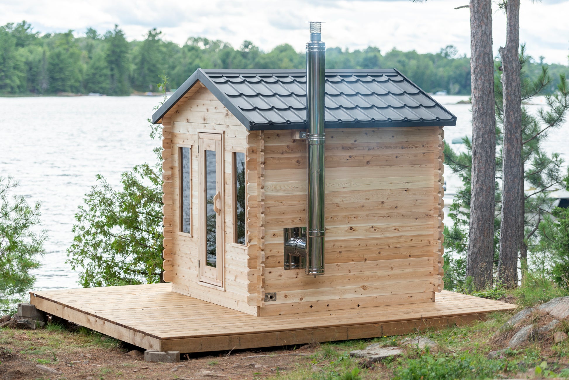 Wooden cabin on a platform by a lake with trees in the background