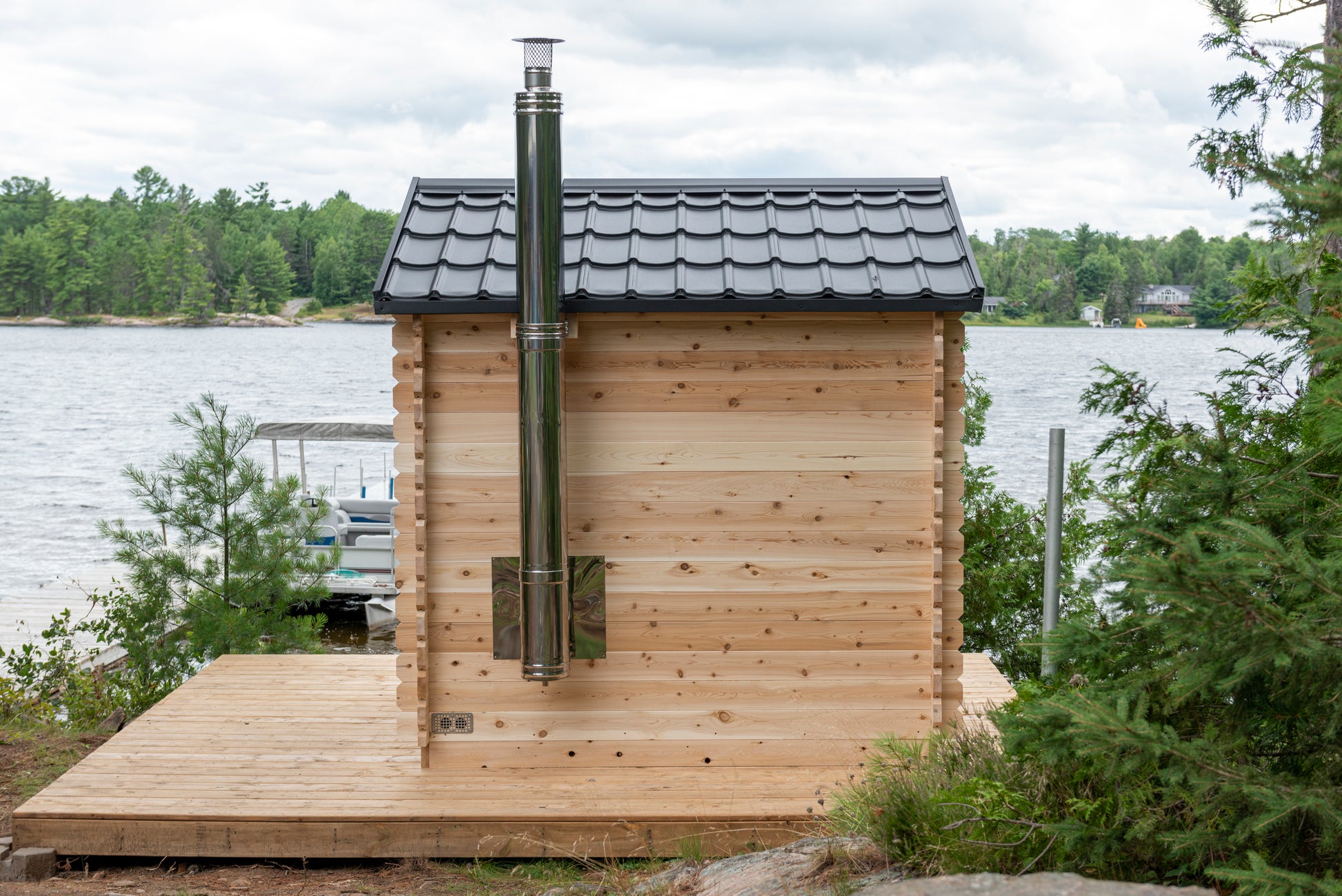 Wooden cabin with a chimney near a body of water and trees