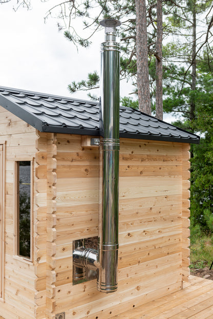Wooden cabin with a metal chimney pipe against a forest background