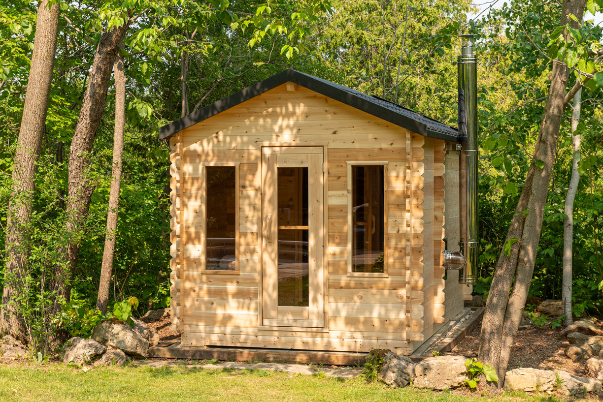Wooden cabin in a forest setting with trees and greenery around.