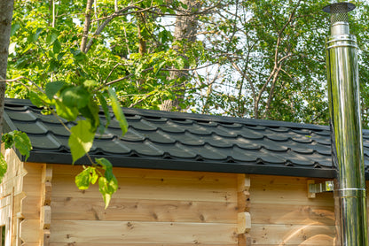 Wooden cabin with a black roof and metal chimney in a forest setting