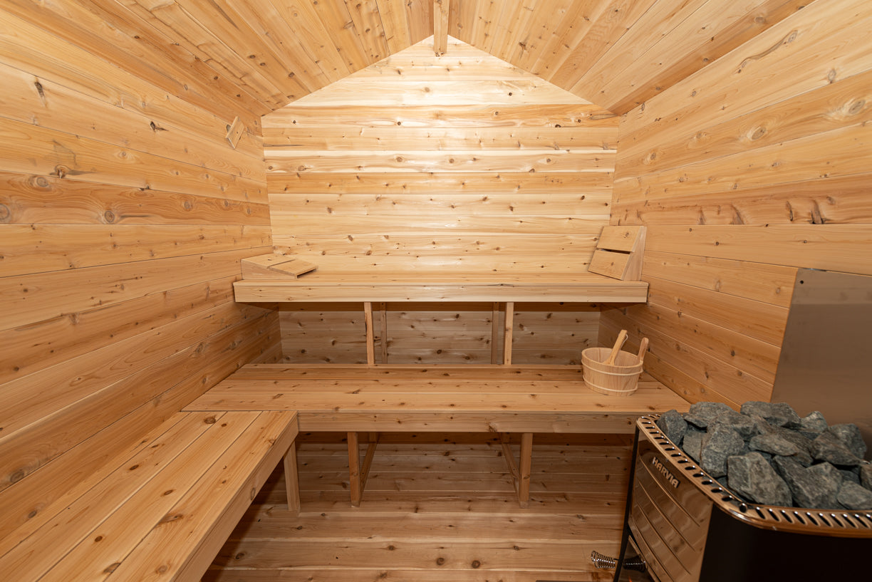 Wooden sauna interior with benches and a basket of stones.