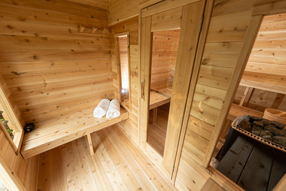 Wooden sauna interior with benches, towels, and a mirror.