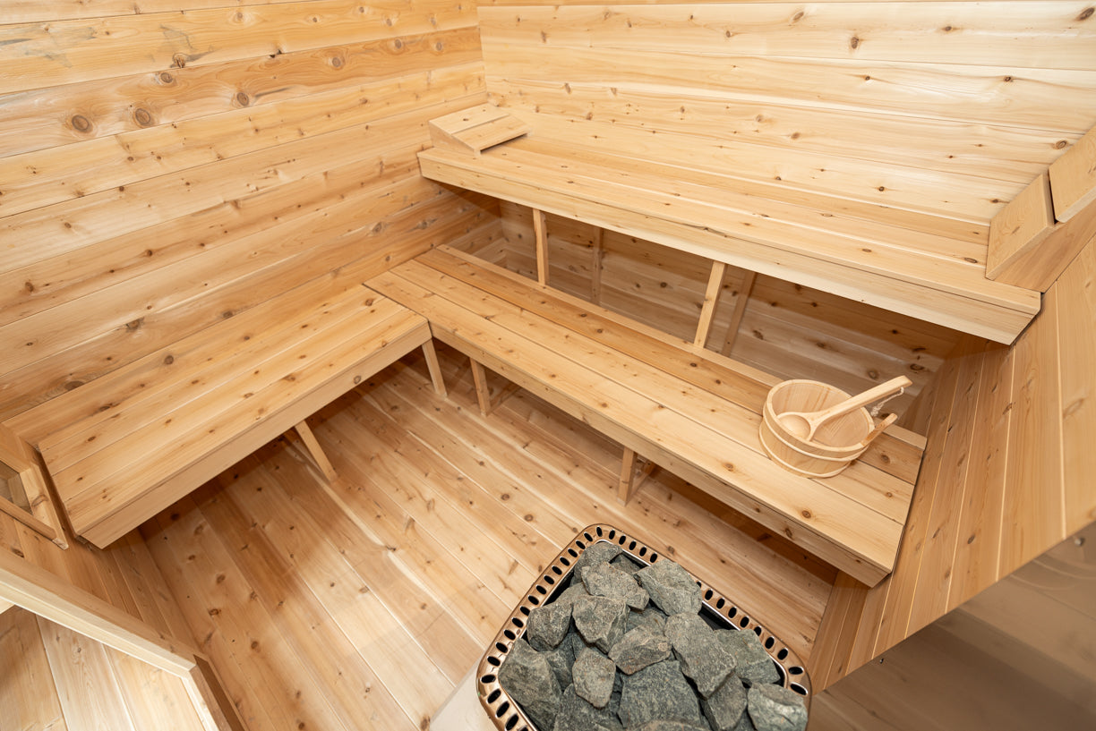 Wooden sauna interior with benches and a basket of stones.