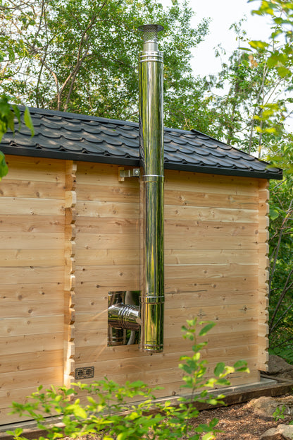 Wooden cabin with a metal chimney pipe in a forest setting