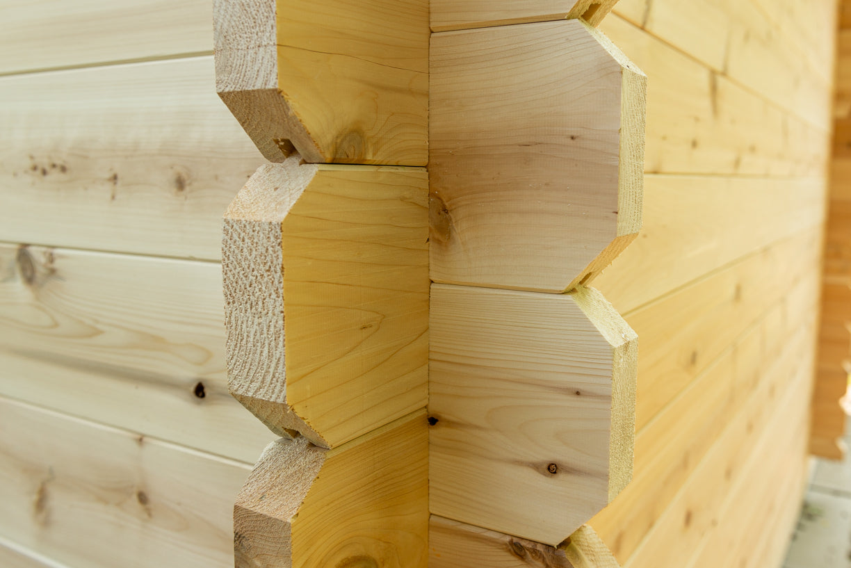 Close-up of a wooden log cabin wall with dovetail joints.