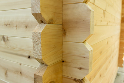 Close-up of a wooden log cabin wall with dovetail joints.