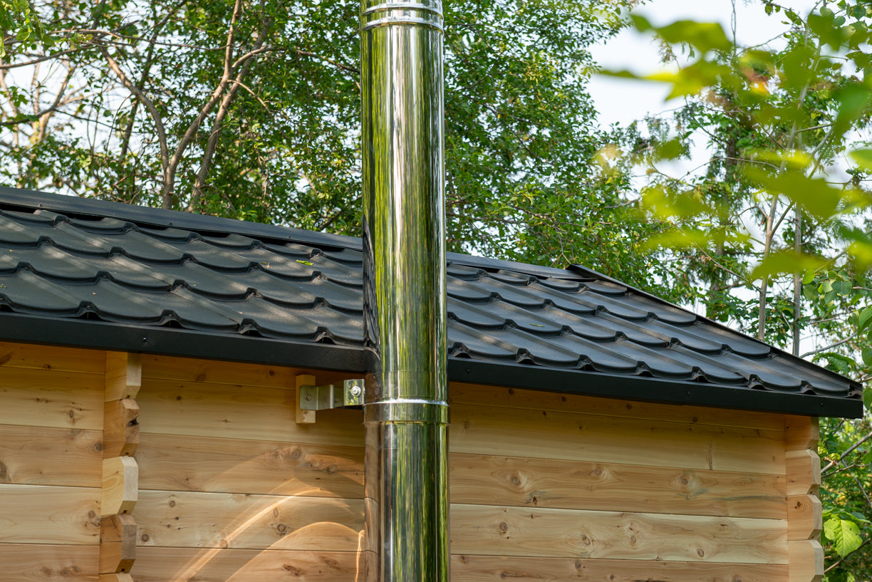 Wooden cabin with a metal chimney pipe against a forest background