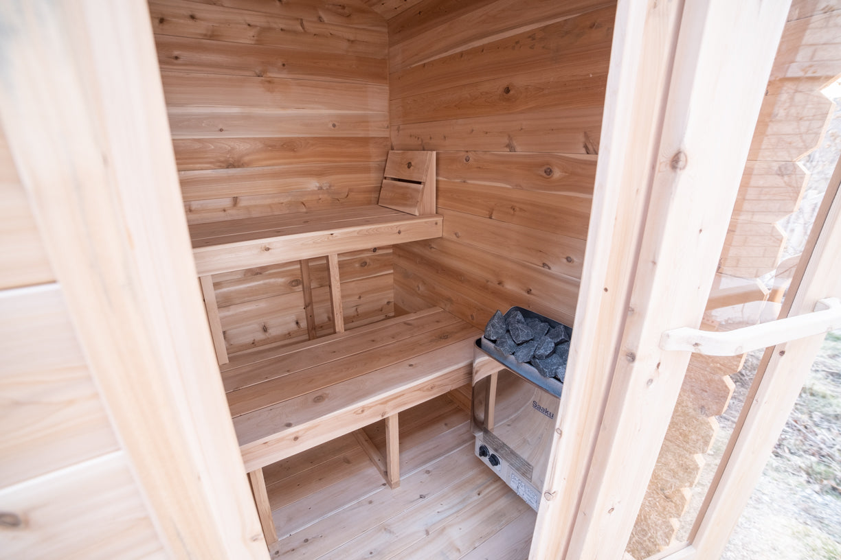 Wooden sauna interior with benches and a stone for heat.