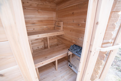 Wooden sauna interior with benches and a stone for heat.