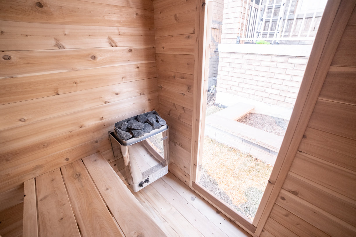 Wooden sauna interior with a window and stone electric heater.