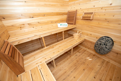 Wooden sauna interior with benches and a basket of stones.