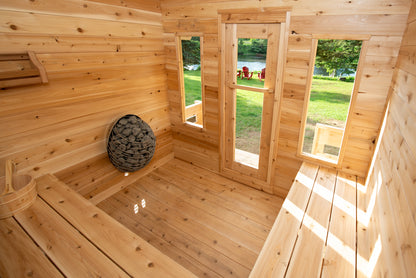 Wooden sauna cabin interior with a view of a grassy area outside.