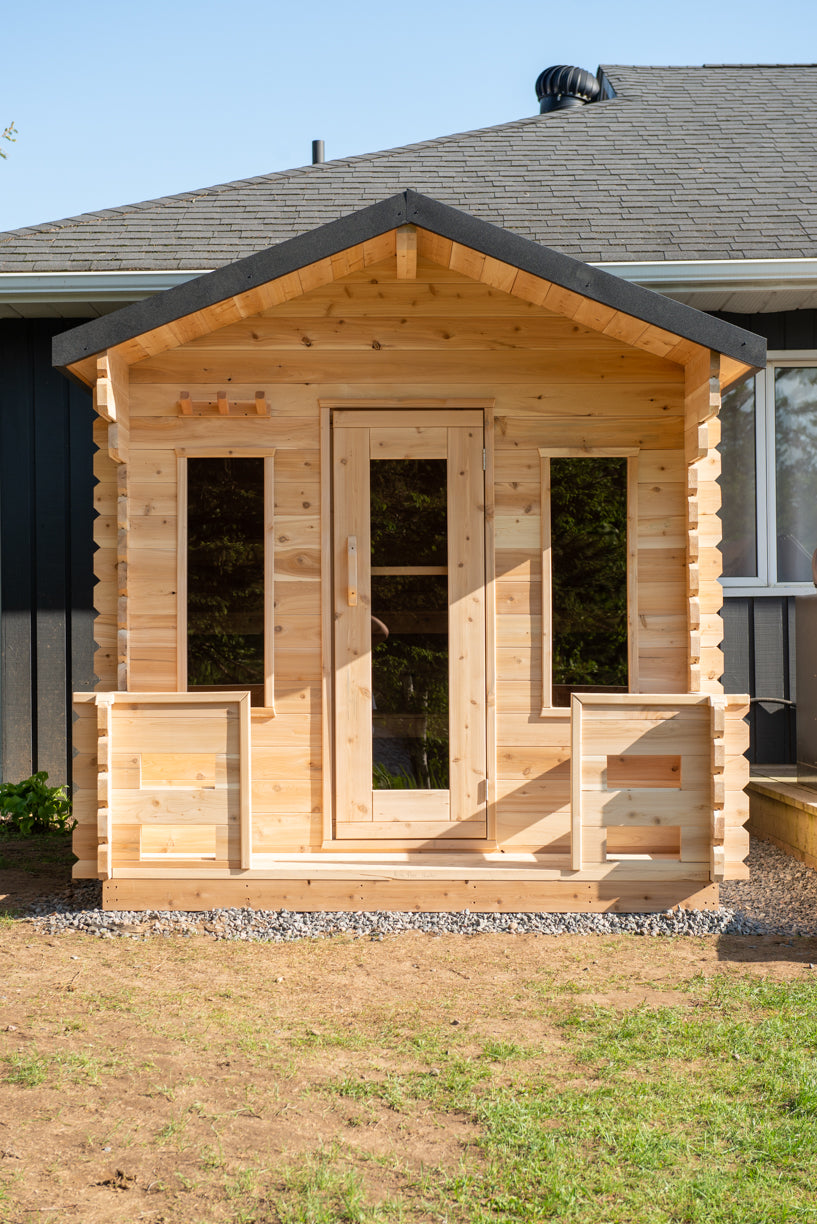 Wooden cabin sauna with porch and a door and windows on a grassy area