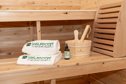 Wooden sauna bench with Leisurecraft towels, bucket, and bottle on a wooden background