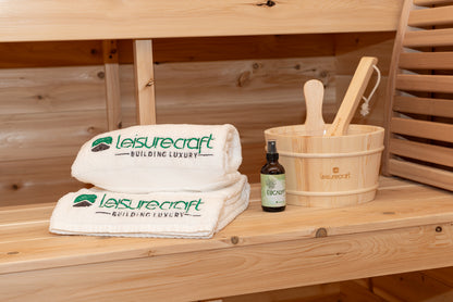 Leisurecraft branded towels, bottle, and wooden bucket on a wooden surface