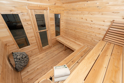 Wooden sauna interior with benches, towels, and a stone heater.