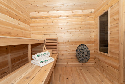 Wooden sauna interior with towels and a Huum electric heater with a wooden bench.