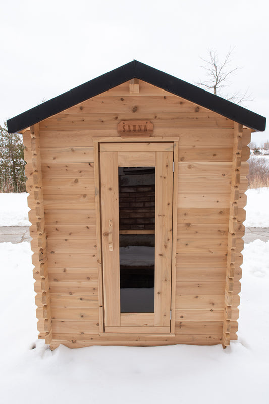 Wooden sauna with a black roof in a snowy landscape