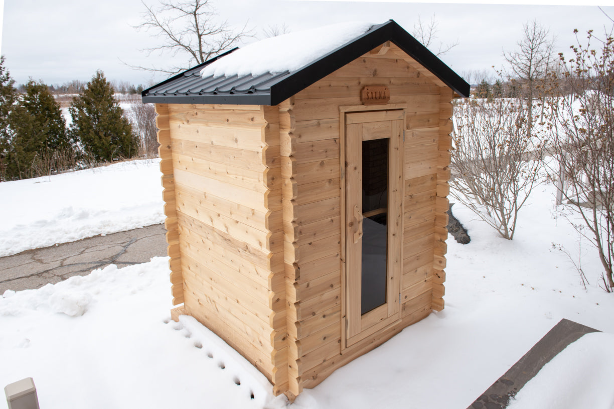 Wooden sauna with a snow-covered roof in a snowy landscape