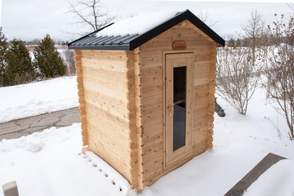 Wooden sauna with a snow-covered roof in a snowy landscape