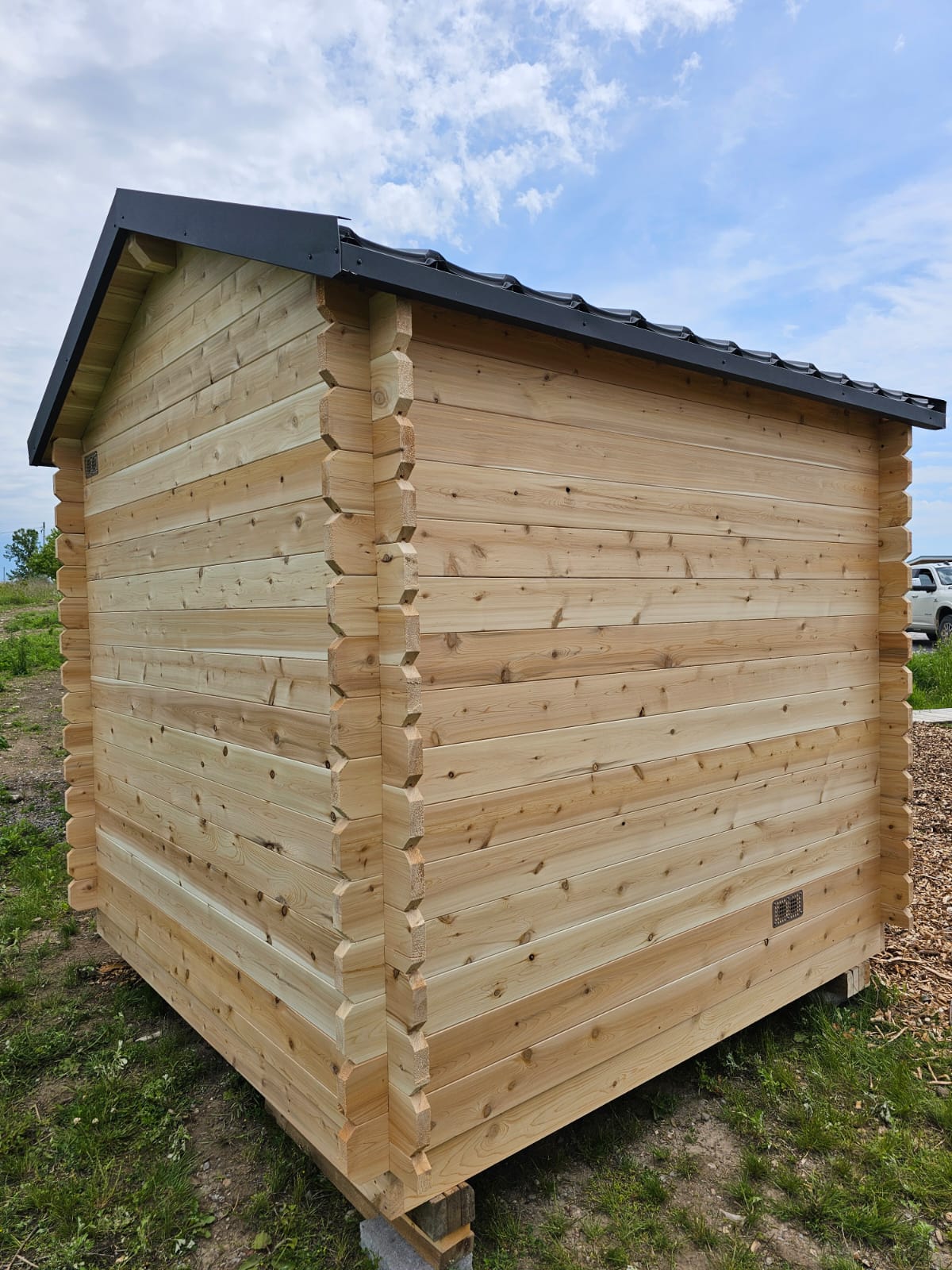 Wooden shed with a black roof in an outdoor setting