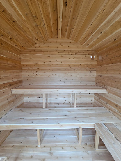 Wooden interior of a small cabin with benches and a sloping ceiling.
