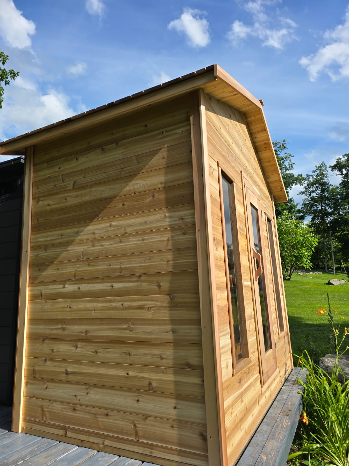 Wooden cabin with a grassy area and trees in the background