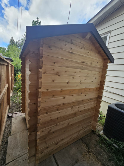 Wooden sauna with a black roof in a backyard setting