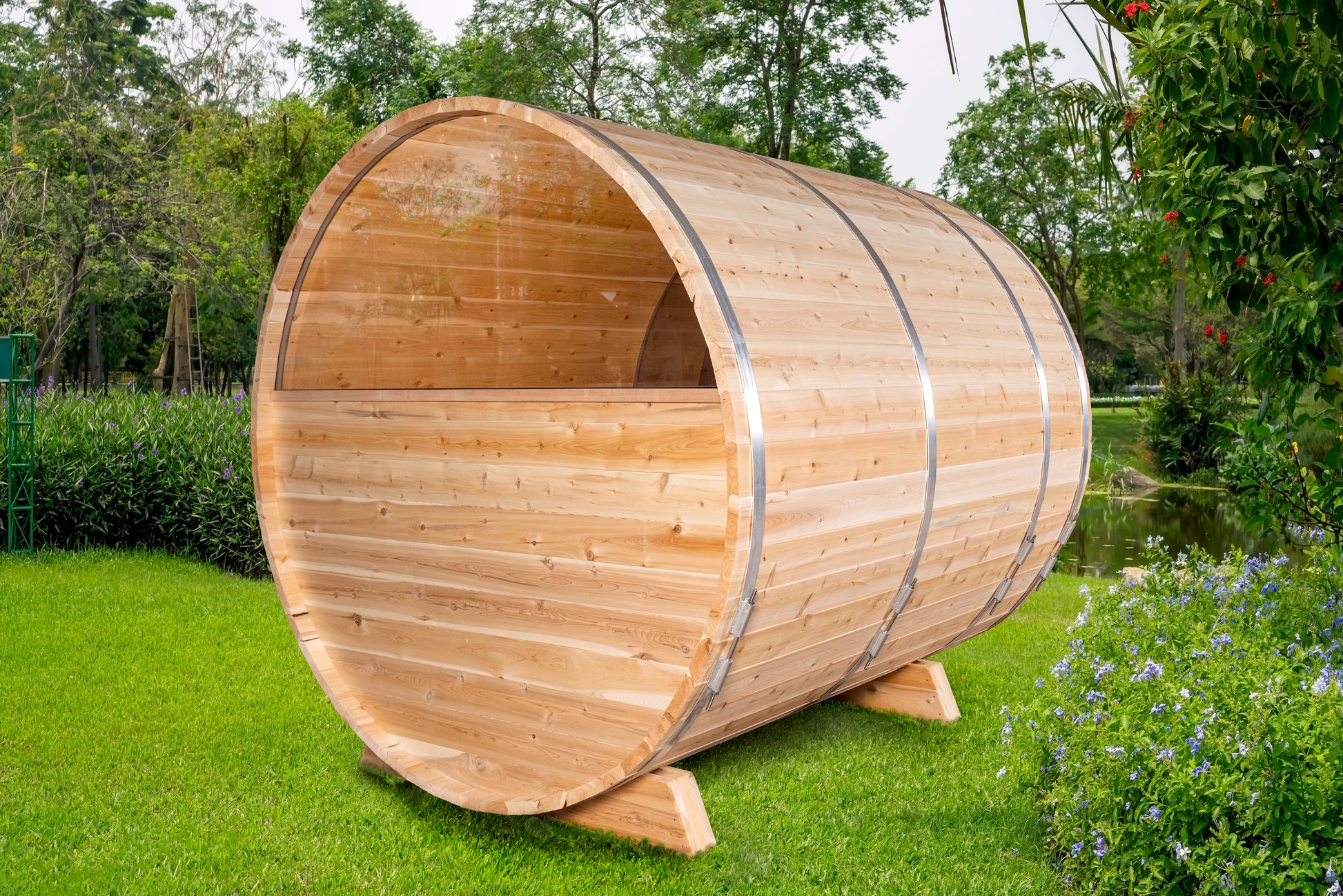 Wooden barrel-shaped outdoor sauna in a garden setting with greenery.