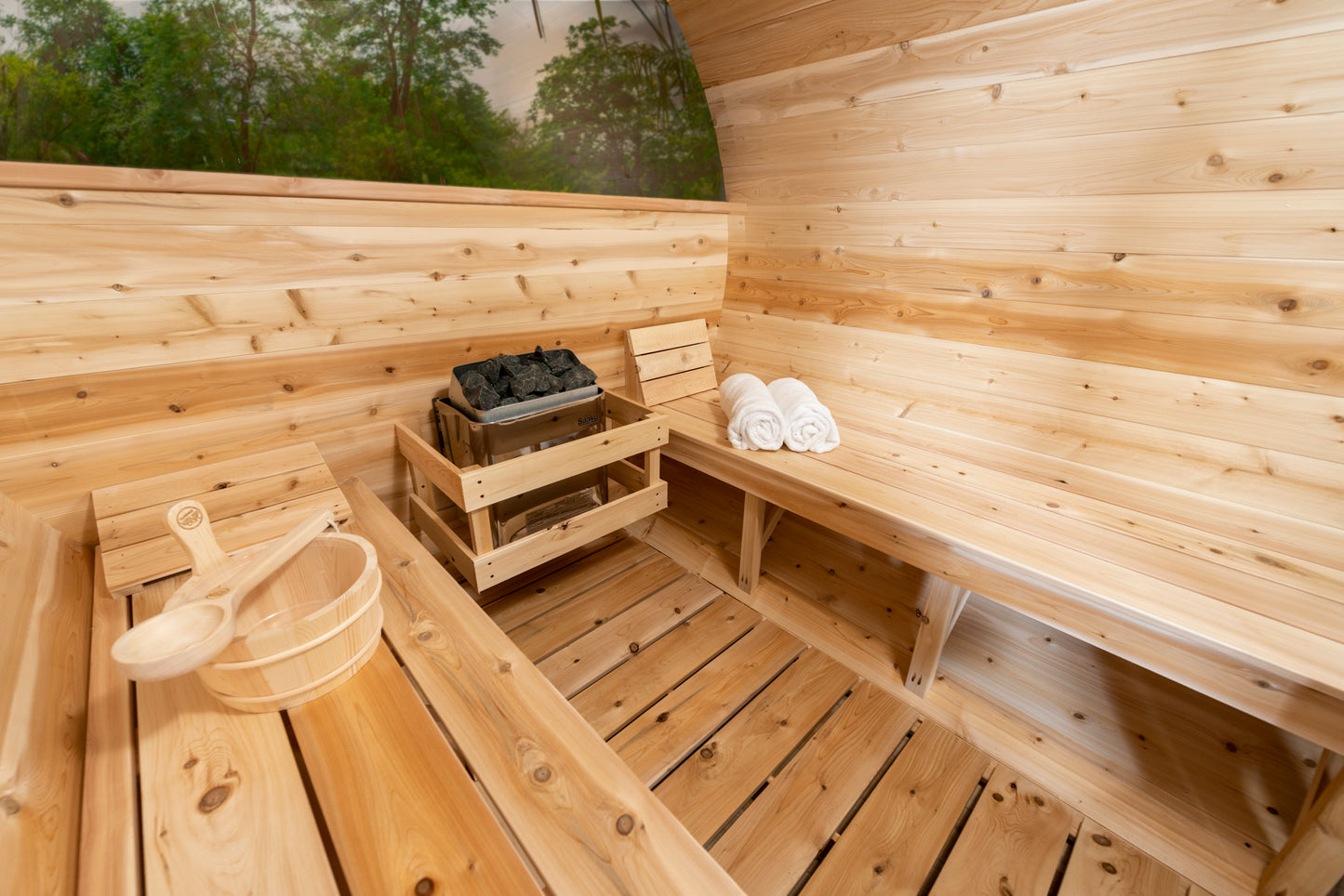 Wooden sauna interior with benches, towels, and a bucket.