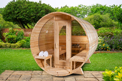Wooden outdoor sauna in a garden setting with greenery.